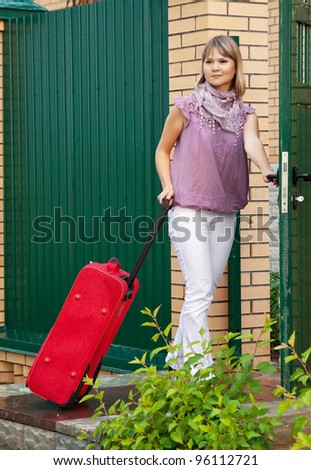 woman with suitcase near fence wicket  in front of home