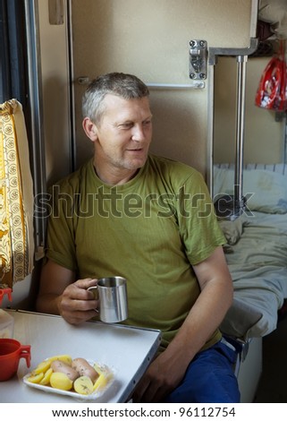 Mature man drinks tea  in sleeper train