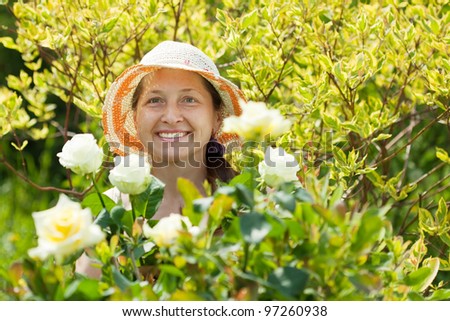 Happy Mature woman in yard gardening with roses plant