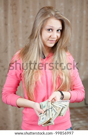 happy casual girl with bundles of US dollars  in home interior