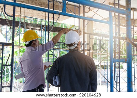 Engineer and Architect working at Construction Site with blueprint