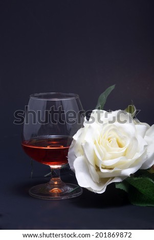 wine glass with red sparkling drink poured in and white roses