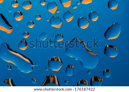 drops of water with orange reflection on blue background