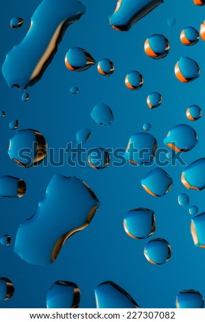 drops of water with orange reflection on blue background