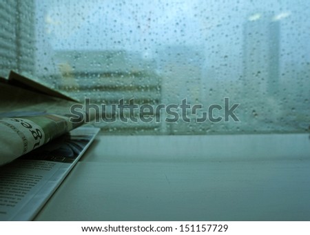 newspaper at office window with rain outside