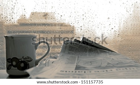 Cup of coffee,-newspaper and rain outside window