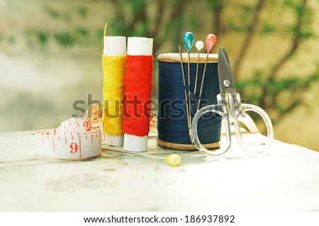 old style image of cotton reels and other sewing items on a wooden table