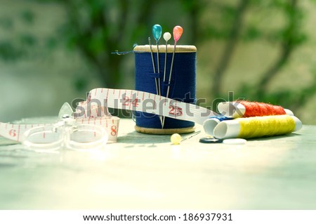 old style image of cotton reels and other sewing items on a wooden table