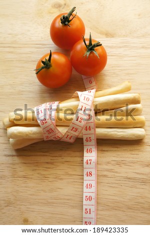 Healthy food concept, stick biscuits wrapping with measuring tape and tomatoes