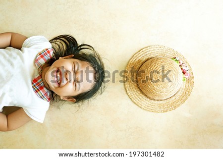 Little asian girl laying on the floor with hat