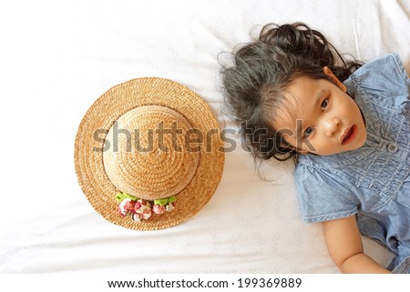 Little asian girl laying on bed with hat
