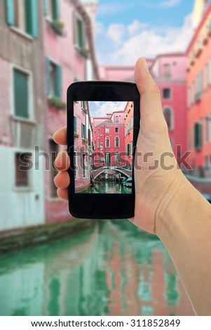 travel concept - tourist taking photo of canal, gondola, boats in Venice, Italy on mobile gadget