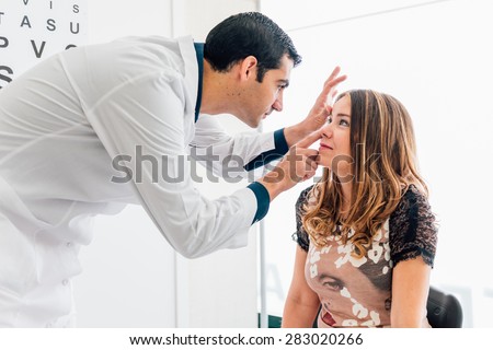 optometry concept - pretty young woman having her eyes examined by an eye doctor