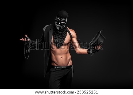 a man in a black mask with metal elements in black semi-jacket on a black background