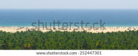 Beautiful view for relaxation - serene vast panorama of the sea, the beach with fishing boats and tropical jungle from the heights in the coastal hills of Kerala in southern India.