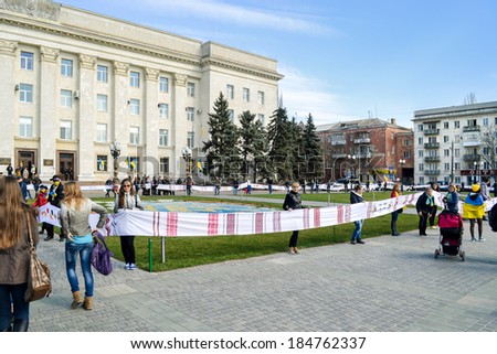 KHERSON, UKRAINE - MARCH 30, 2014: people unfold extremely long Ukrainian traditional embroidered by hand towel to integrity of Ukraine and to 70th jubilee of institution of Kherson region.