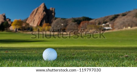 White Golf Ball on the Green With Giant Red Rocks in the Background
