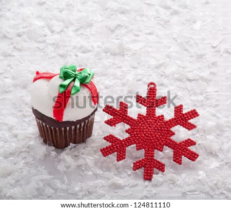 Chocolate Christmas Cupcake With White and Red Frosting and a Green Bow Surrounded by Red Beads, Snow and Red Snowflake