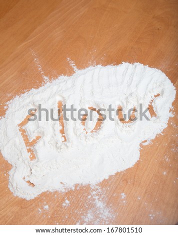 The Words Flour Spelled in Freshly Sifted Flour on Wooden Chopping Board