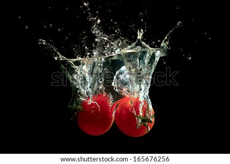Fresh tomato splash under water on black background
