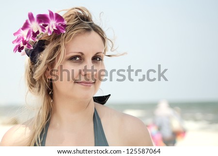 Portrait of a woman with orchid in her hair at the beach