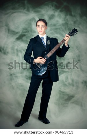 Young formal man playing on a guitar, smoke on a background