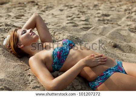 Beautiful young woman having rest on river beach