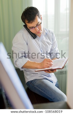 Self-employed man working at home. Talking on phone