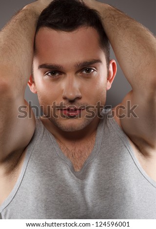Handsome young male fashion model, wearing in grey singlet. Studio shot