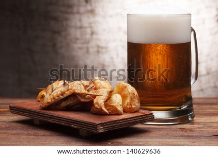 One glass of beer and grilled chicken wings