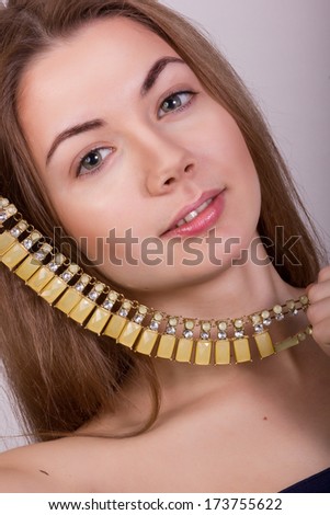 Portrait of beautiful young brown-haired woman without makeup in a necklace with yellow stones