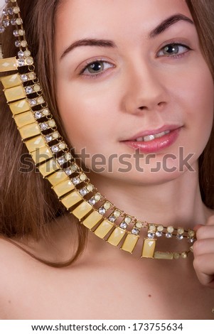 Portrait of beautiful young brown-haired woman without makeup in a necklace with yellow stones