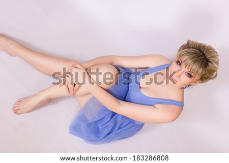Portrait of a beautiful young blonde woman with short hair and dressed in a blue short dress. Girl posing with different emotions in the studio.