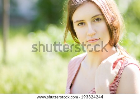 Portrait of a beautiful young woman with brown hair in retro plaid dress. Girl posing in nature with a small bouquet of violets