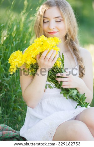 Closeup portrait of cute young girl with yellow flowers smiling outdoors. Soft focus