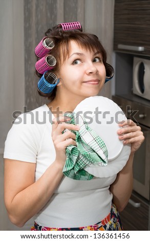 Housewife wipes plate and dreams in kitchen