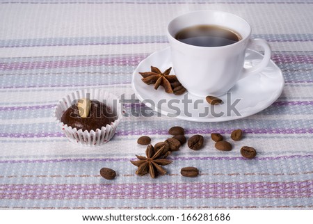 Cup of coffee decorated beans and star anise with fresh almond cakes on a striped napkin
