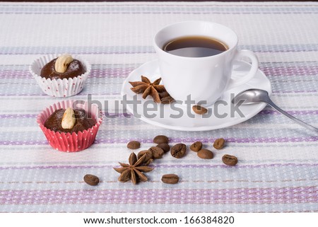 Cup of coffee decorated beans and star anise with fresh almond cakes on a striped napkin