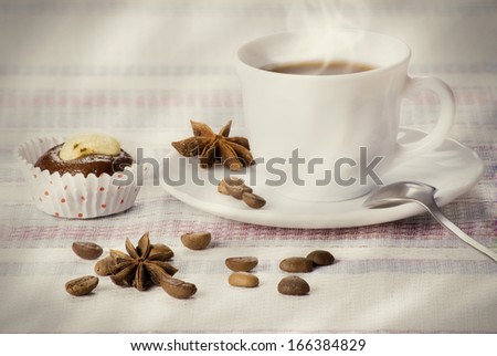 Cup of coffee decorated beans and star anise with fresh almond cakes on a striped napkin. Morning concept.