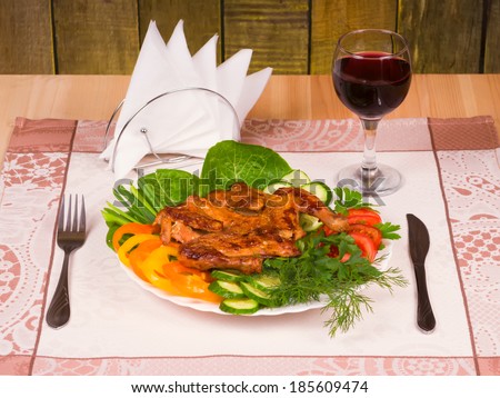 Grilled Chicken Tapakats (Tabaka) with vegetables and glass of red wine on table in wooden restaurant interior. Georgian cuisine.