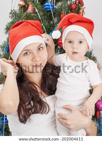 Happy family near the Christmas tree celebrate New Year. Mom and kid at Christmas tree. Mother and child on Christmas Eve. Mummy and Baby.