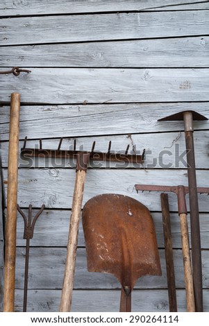 The old rusty tradition tools, instruments, implements and farm or household equipment on wooden shed wall background