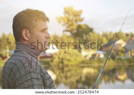 Fisherman with a fishing rod, sunset landscape