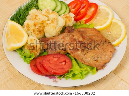 Grilled pork chop with a side dish of cauliflower and vegetables on the plate
