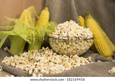 Corn on the cob and popcorn in glass and spilled on the table