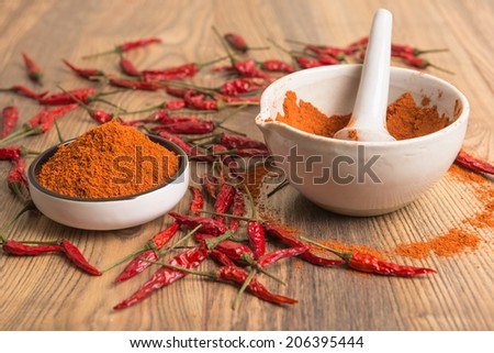 red hot pepper chili powder in a mortar and pods on a wooden table