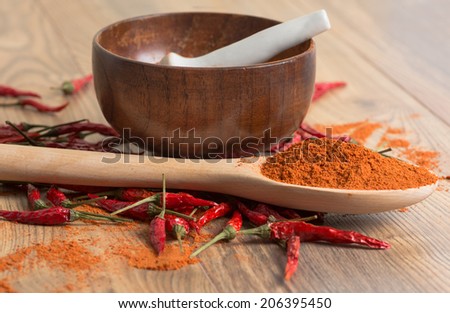 red hot pepper chili powder in a mortar and pods on a wooden table