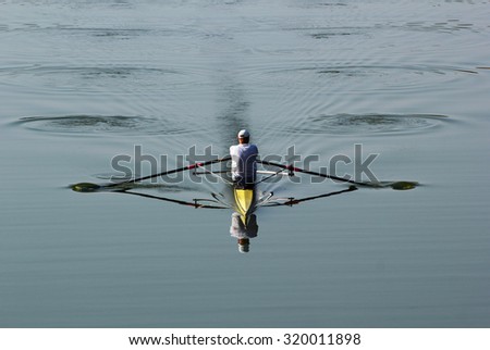 One rower in a boat, rowing on the tranquil river. soft focus.