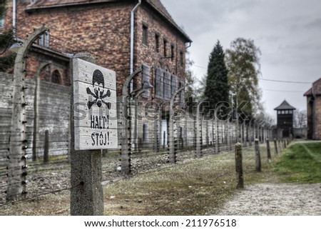 AUSCHWITZ, POLAND - APRIL 4: Warning sign in front of an electric fence in the concentration camp of Auschwitz on April 4 2014. To many, Auschwitz is the place most closely related to the Holocaust.