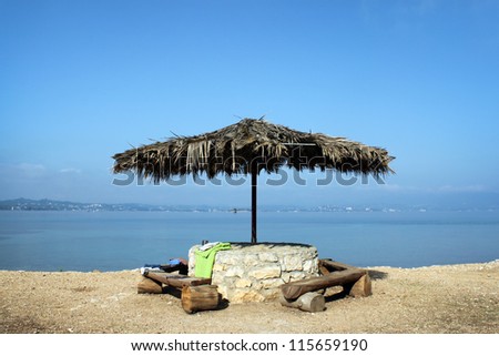 a large straw umbrella from the sun on the shore of the sea with a stone Foundation